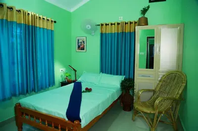 a bedroom with a bed and a chair and blue curtains at Puzhayoram home stay, Palakkuli, Mananthavadi wayanad kerala in Mananthavady