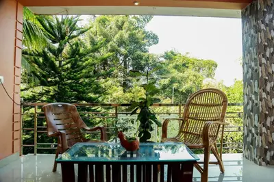 a room with a table and chairs on a balcony at Puzhayoram home stay, Palakkuli, Mananthavadi wayanad kerala in Mananthavady