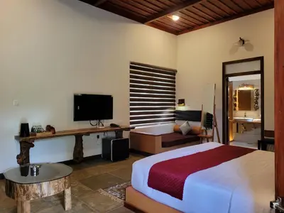 a bedroom with a bed and a desk and a television at Aalterra by The Almanac in Wayanad