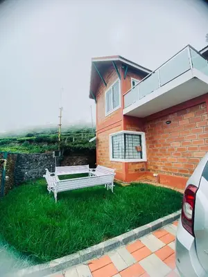 a white bench sitting in the grass in front of a house at S ELLA Residency in Kotagiri