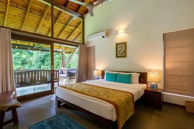 a bedroom with a large bed and a balcony at amã Stays & Trails - The Old Cattleshed, Wayanad in Wayanad