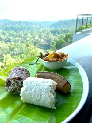 a plate of food on top of a green leaf at GReaT Trails Wayanad by GRT Hotels in Wayanad