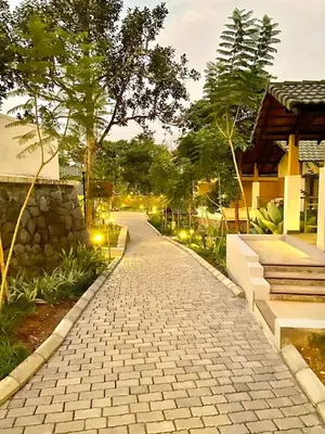 a cobblestone path in front of a house with lights at GReaT Trails Wayanad by GRT Hotels in Wayanad