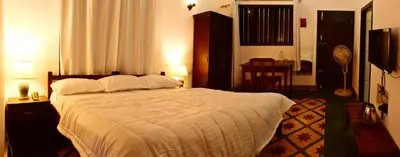 a bedroom with a large bed with white sheets at Nivaasana Bed & Breakfast in Kalpetta