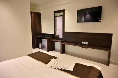 a bedroom with a bed and a tv on the wall at Mysore Royale in Mysore