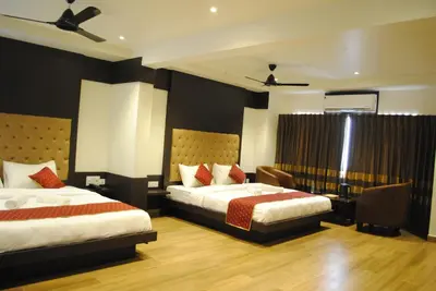 a hotel room with two beds and a desk at Mysore Royale in Mysore