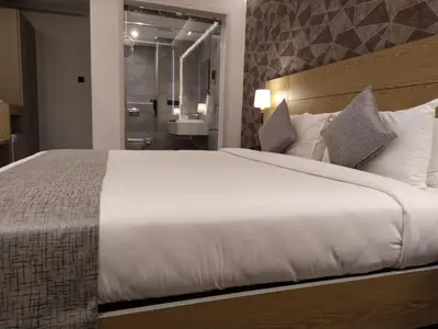 a bedroom with a large white bed and a bathroom at MothiMahal Residency Thrissur in Trichūr