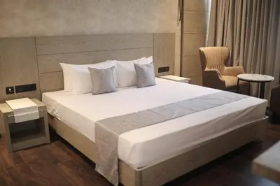 a bedroom with a large white bed and a chair at MothiMahal Residency Thrissur in Trichūr