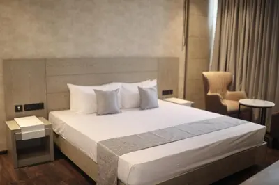 a bedroom with a bed with white sheets and pillows at MothiMahal Residency Thrissur in Trichūr