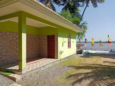 a small yellow and green building with a red door at Kalamana Serene in Chāvakkād