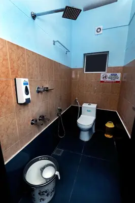 a bathroom with a toilet and a tv on the wall at NARMADA POOL VILLA (KAVERI) in Perintalmanna