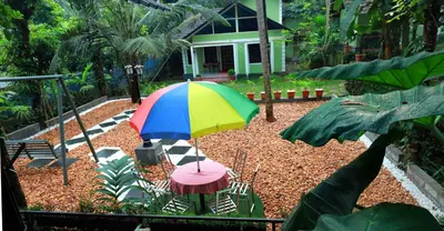 a colorful umbrella and two chairs and a table at NARMADA POOL VILLA (KAVERI) in Perintalmanna