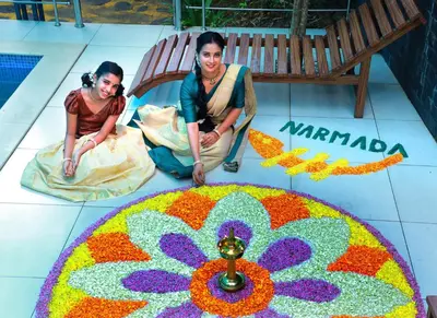 two people sitting in front of a rangoli on a floor at NARMADA POOL VILLA (KAVERI) in Perintalmanna