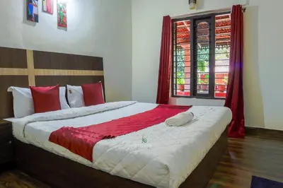 a bedroom with a large bed with red and white pillows at D signature Homestay By Lexstays in Kushālnagar