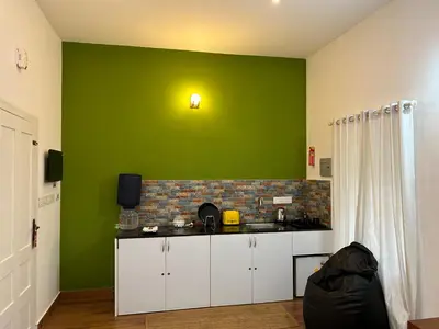 a kitchen with a green wall with a counter top at Silver Oak By Exuberance Stays (Independent Holiday Home) in Wayanad