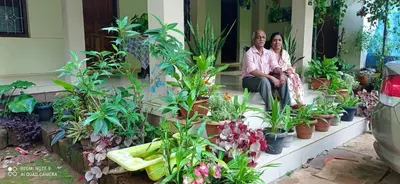 two people sitting on a porch with potted plants at NARAYANALAYAM-Vintage Retreat-Homestay & Rest'Inn in Kannur