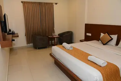 a hotel room with a large bed and a television at Sai Vihaar Inn & Suites in Mysore