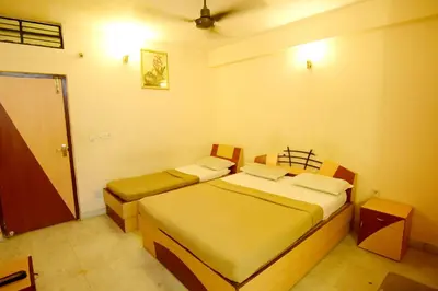 a bedroom with two beds and a door to a room at Shastri Paradise opst to KSRTC Bus Stand in Mysore