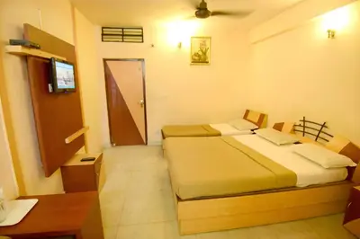 a bedroom with two beds and a table and a door at Shastri Paradise opst to KSRTC Bus Stand in Mysore
