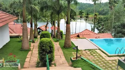 an aerial view of a resort with a swimming pool and palm trees at The Wave Lakeview Resort & Spa in Wayanad