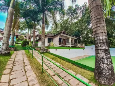a tennis court in front of a house with palm trees at The Wave Lakeview Resort & Spa in Wayanad