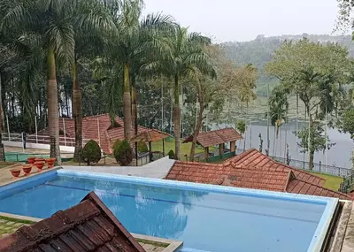 a large swimming pool with palm trees and a lake at The Wave Lakeview Resort & Spa in Wayanad