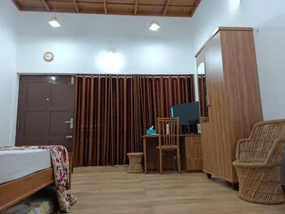 a bedroom with a bed and a cabinet and a tv at Beach Nest in Kannur