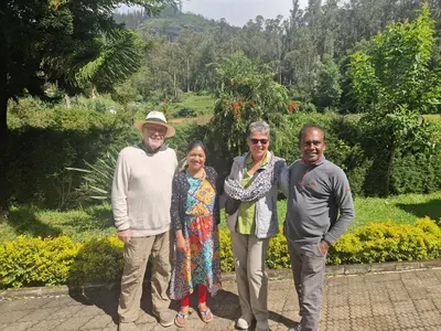 a group of people posing for a picture in a garden at Narmada Holiday Home in Ooty