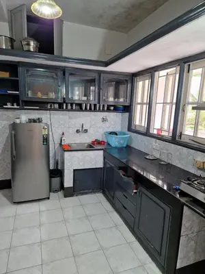 a kitchen with a stainless steel refrigerator and counters at Narmada Holiday Home in Ooty