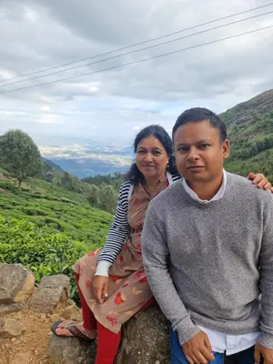 a woman and a man sitting on a rock at Narmada Holiday Home in Ooty