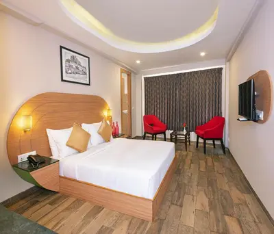a hotel room with a bed and a television at Mango Hill Central Ooty in Ooty