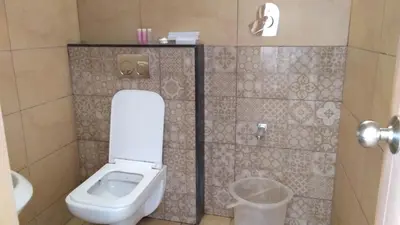 a bathroom with a toilet and a trash can at Mango Hill Central Ooty in Ooty