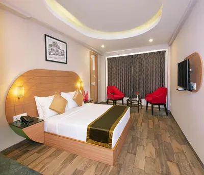 a hotel room with a bed and a television at Mango Hill Central Ooty in Ooty