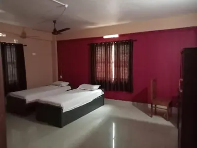 two beds in a room with a red wall at SAFA RESIDENCY in Perintalmanna