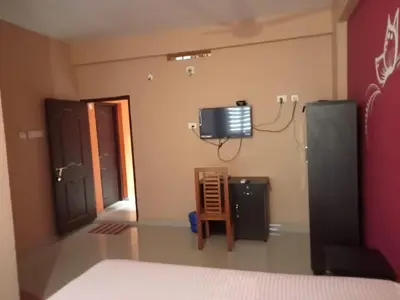 a room with a tv on the wall and a chair at SAFA RESIDENCY in Perintalmanna
