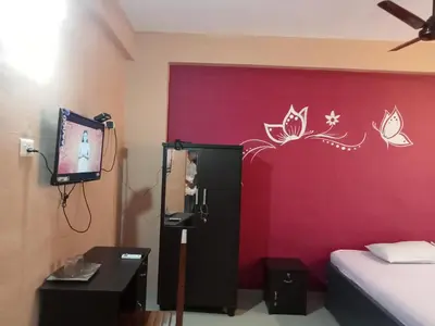 a bedroom with a red wall with a bed and a tv at SAFA RESIDENCY in Perintalmanna
