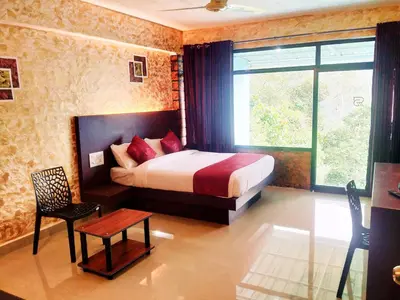 a bedroom with a bed and a table and a chair at Rambler Garden Resort in Idukki