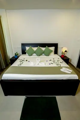 a bedroom with a large bed with green pillows at SATRA WAYANAD in Kalpetta