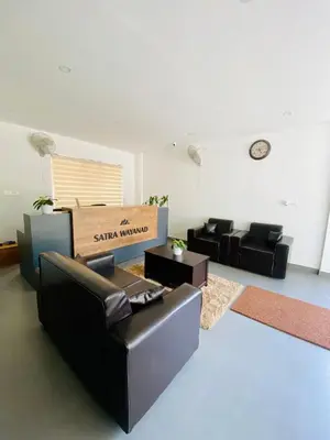 a living room with a couch and chairs and a table at SATRA WAYANAD in Kalpetta