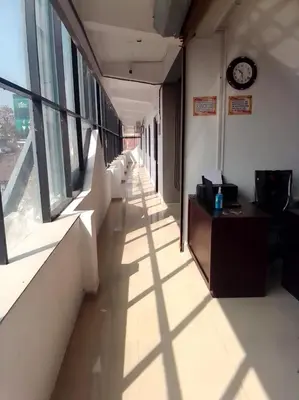 a hallway in an office building with a clock on the wall at Emirates Residency in Pudunagaram