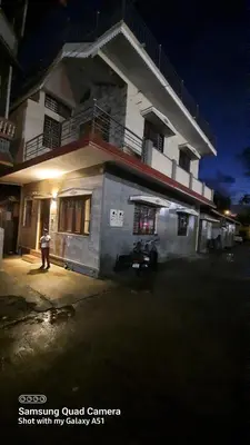 a person standing in front of a building at night at Varam Homestay in Madikeri