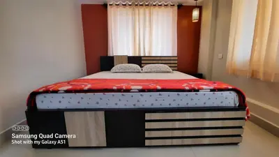 a bed in a room with a red and white mattress at Varam Homestay in Madikeri