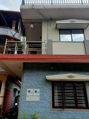 a blue building with a balcony on top of it at Varam Homestay in Madikeri