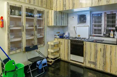 a kitchen with wooden cabinets and a stove at Belljem Homes -your own private resort -5 BHK in Trichūr