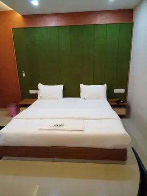 a bedroom with a large bed with a green headboard at GRACE RESIDENCY in Tirūr