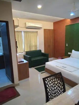 a hotel room with a bed and a green couch at GRACE RESIDENCY in Tirūr