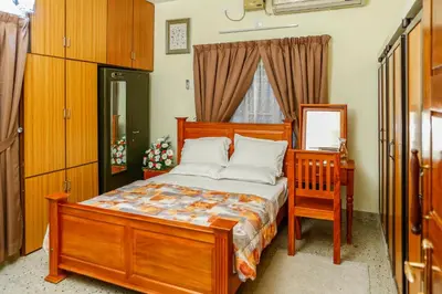 a bedroom with a wooden bed and a chair and a mirror at Belljem Homes -your own private resort -2 BHK GF in Trichūr