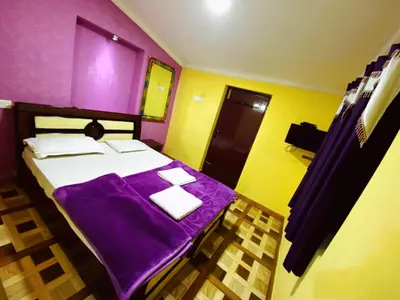a bedroom with a bed with purple sheets and towels at MAGIC MIST RESORT in Ooty