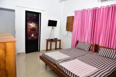a bedroom with a bed and a pink curtain at Oceangreen cottage in Kannur