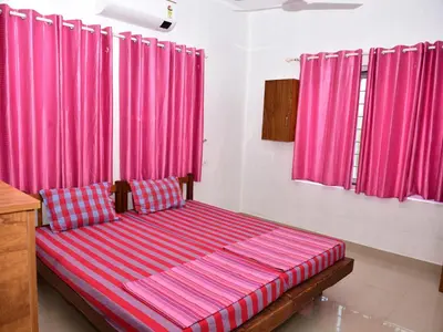 a bed in a room with pink curtains at Oceangreen cottage in Kannur